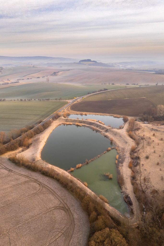 Rybníky uprostřed zemědělské krajiny v měkkém ranním světle s nízkou oblačností
