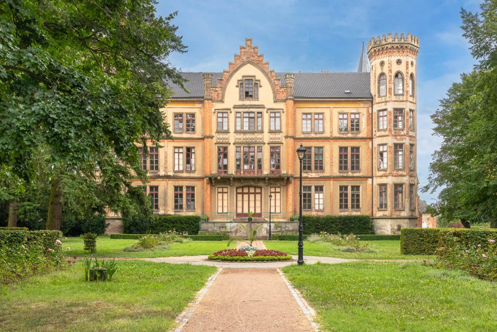 Pohled na zámek Bzenec ze zámecké zahrady. Modrá obloha se skvěle doplňuje s pískovou omítkou zámku a rozkvetlou zahradou