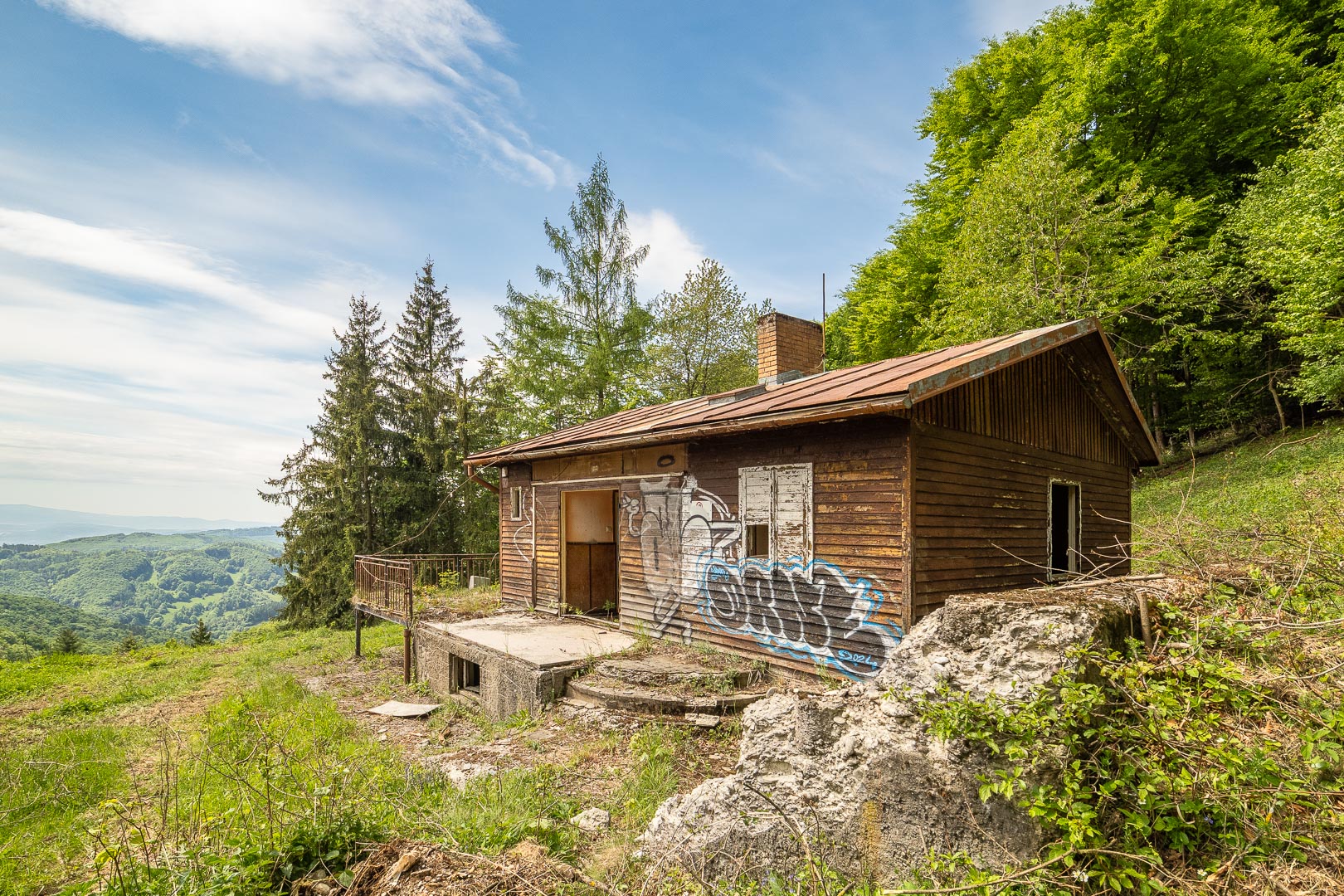 Zchátralá chata v horách u lesa